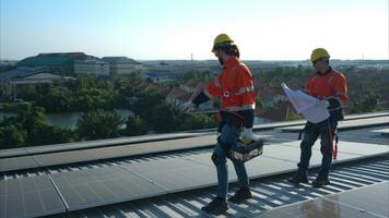 både av tekniker är montera sol- paneler på de tak av de lager till förändra sol- energi in i elektrisk energi för använda sig av i fabriker. foto