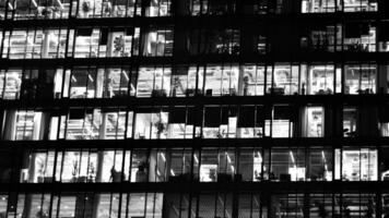 mönster av kontor byggnader fönster upplyst på natt. glas arkitektur ,företags byggnad på natt - företag begrepp. svart och vit. foto
