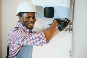 afrikansk amerikan arbetstagare uppsättning upp central gas uppvärmning panna på Hem foto