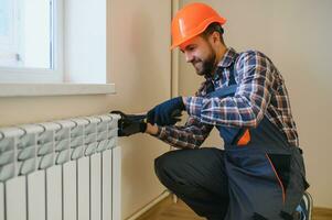 uppvärmning systemet installation och underhåll service. rörmokare montera radiator foto