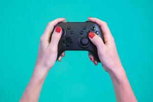 pOV av kvinna händer gaming med video spel kontrollant gamepad isolerat på en blå bakgrund studio. foto