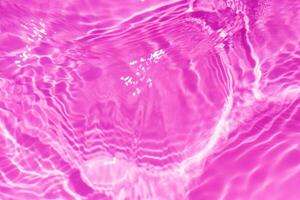 lila vatten stänk på de yta krusning fläck. defokusering suddig transparent rosa färgad klar lugna vatten yta textur med stänk och bubbla. vatten vågor med lysande mönster textur bakgrund. foto