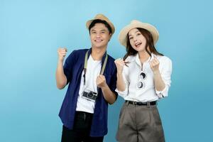 överraskad asiatisk turist par i sommar kläder och höjning nävar i Framgång på blå bakgrund foto