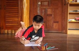 en pojke sitter hemma och tecknar och målar. foto