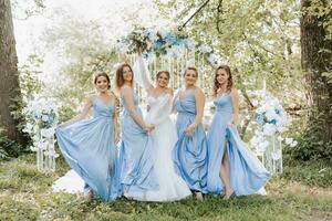 de brudtärnor i blå klänningar, glädjas, de brud är innehav en skön bukett. skön lyx bröllop blog begrepp. vår bröllop. foto