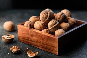 närbild av valnötter i ett skal i en trälåda på ett bord. foto
