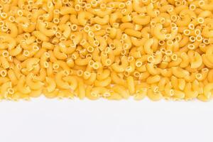 okokt chifferi rigati pasta spridd på vit tabell. fett och ohälsosam mat. klassisk torr makaroner. italiensk kultur och kök. rå pasta foto