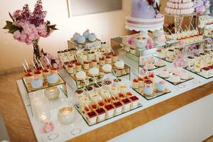 utsökt bröllop reception godis bar efterrätt tabell full med kakor och sötsaker och blommor kinesisk körsbär blommar på de bakgrund av ett utsökt restaurang foto