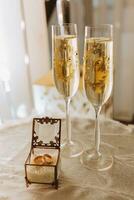 bröllop glasögon är fylld med champagne. bröllop ringar och förberedelse för de bröllop ceremoni. skön ljus foto