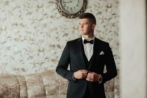 porträtt. en man i en vit skjorta, en svart rosett slips och en svart kostym poser i en rum. en eleganta Kolla på. herr- stil. mode. företag foto