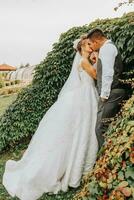 brud och brudgum i de trädgård bland grönska. kunglig bröllop begrepp. chic brudens klänning med en lång tåg. ömhet och stillhet. porträtt fotografi foto