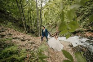 de brudgum innehar de brudens hand och leder henne upp de kulle. bröllop Foto session i natur. Foto session i de skog av de brud och brudgum.