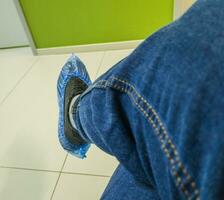 person i de jeans bär sko omslag i de klinik. sjukvård foto