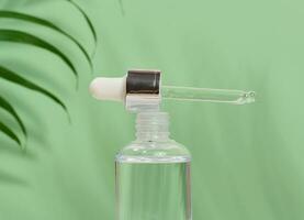 glas flaska för kosmetika, oljor med en pipett på en grön bakgrund foto