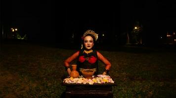 en kvinna dansare utför en ritual den där skapar en magisk och mystisk atmosfär i främre av blomma offer foto