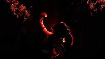 de silhuett av en kvinna dansare innehav gnistrande Smycken och ser skarp i de mörk med brand brinnande i de bakgrund foto