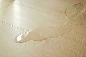 spillts vatten droppar på trä- laminera golv. foto
