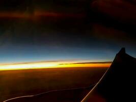utanför fönster se av flygplan med flygplan vinge och himmel av soluppgång bakgrund. foto
