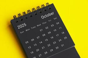 oktober 2025 svart och vit skrivbord kalender på gul omslag bakgrund. kalender begrepp foto