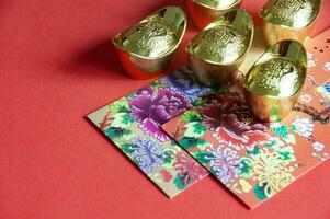 färgrik kuvert och gyllene göt på röd omslag bakgrund med kinesisk ny år lyckönskningar foto