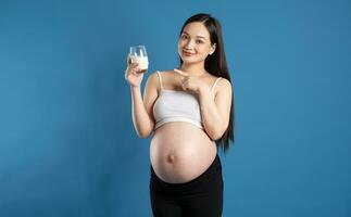 porträtt av gravid asiatisk kvinna, isolerat på blå bakgrund foto