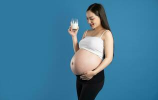 porträtt av gravid asiatisk kvinna, isolerat på blå bakgrund foto