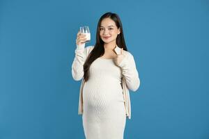 porträtt av gravid asiatisk kvinna, isolerat på blå bakgrund foto