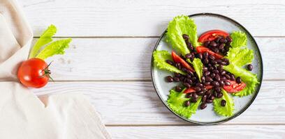 vegetarian sallad av svart bönor, tomater och sallad på en tallrik topp se webb baner foto