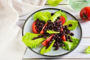 vegetarian sallad av svart bönor, tomater och sallad på en tallrik foto