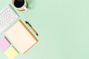 kreativt plattläggningsfoto av skrivbordet på arbetsytan. ovanifrån kontorsbord med tangentbord och öppen mockup svart anteckningsbok på pastellgrön bakgrund. ovanifrån håna med kopia utrymme fotografering. foto
