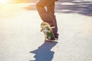 närbild ben av tonåring spelar en skateboard på offentlig parkens väg. foto