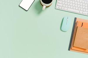 minimalt arbetsutrymme - kreativt plattläggningsfoto av arbetsytans skrivbord. ovanifrån kontorsbord med tangentbord, mus och anteckningsbok på pastellgrön bakgrund. ovanifrån med kopieringsutrymme, plattfotografering.