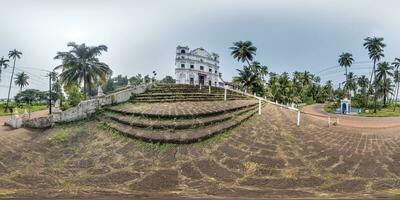 hdri 360 panorama av portugisiska katolik kyrka i djungel bland handflatan träd i indisk tropisk by i likriktad utsprång. vr ar innehåll foto