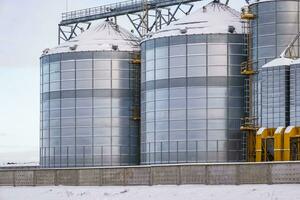 modern jordbruksbearbetning växt för bearbetning och silos för torkning rengöring och lagring av jordbruks Produkter, mjöl, spannmål och spannmål i snö av vinter- fält foto