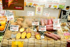 osaka stad, japan -japanska ljuv potatis skiva och ånga på bambu grill med japansk namn och pris etiketter. sälja i kuromon mat marknadsföra. populär till uppäten i de vinter. foto