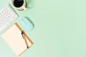kreativt plattläggningsfoto av skrivbordet på arbetsytan. ovanifrån kontorsbord med tangentbord, mus och öppen mockup svart anteckningsbok på pastellgrön färgbakgrund. ovanifrån håna med kopia utrymme fotografering. foto