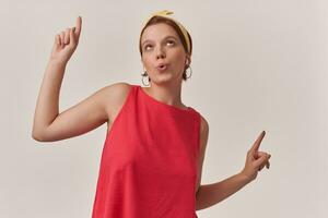 porträtt av europeisk charmig kvinna 20s med naturlig smink bär eleganta sommar trendig röd klänning och gul bandana Framställ isolerat mot vit bakgrund känsla dumbom dans fingrar upp se upp foto