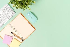 kreativt plattläggningsfoto av skrivbordet på arbetsytan. ovanifrån kontorsbord med tangentbord, mus och öppen mockup svart anteckningsbok på pastellgrön färgbakgrund. ovanifrån håna med kopia utrymme fotografering. foto