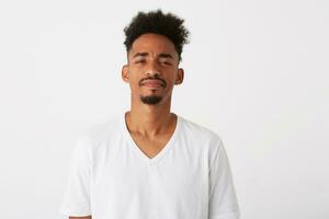porträtt av allvarlig självsäker afrikansk amerikan ung man med lockigt hår bär t skjorta utseende fundersam och tänkande isolerat över vit bakgrund foto