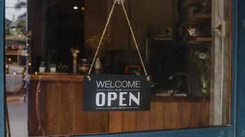 Välkommen, vi är öppna vintage svartvita retro -skyltar på ett kaffeglasdörrkafé efter karantän. ägare småföretag, mat och dryck, företag öppnar igen koncept. foto