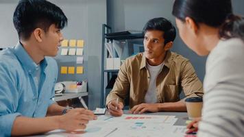 glada unga asiatiska affärsmän och affärskvinnor möter brainstorming några nya idéer om projekt till sin partner som arbetar tillsammans planerar framgångsstrategi njuter av lagarbete i små moderna hemmakontor.