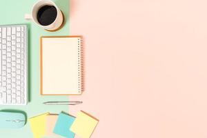 kreativt plattläggningsfoto av skrivbordet på arbetsytan. ovanifrån kontorsbord med tangentbord, mus och öppen mockup svart anteckningsbok på pastellgrön rosa färgbakgrund. ovanifrån håna med kopia utrymme fotografering. foto