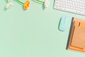 minimalt arbetsutrymme - kreativt plattläggningsfoto av arbetsytans skrivbord. ovanifrån kontorsbord med tangentbord, mus och anteckningsbok på pastellgrön bakgrund. ovanifrån med kopieringsutrymme, plattfotografering.