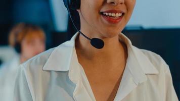 närbild av asiatiska unga call center team eller kundsupport chef med hjälp av dator och mikrofon headset arbetar teknisk support i sen natt kontor. telemarketing eller försäljningsjobb koncept. foto