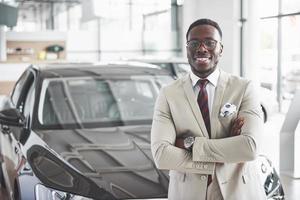 den unga attraktiva svarta affärsmannen köper en ny bil, drömmar går i uppfyllelse foto