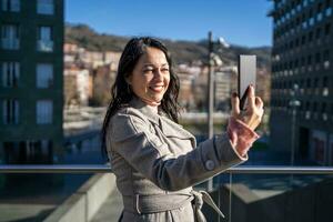 närbild av elegant kvinna tar en selfie med henne smartphone leende. foto