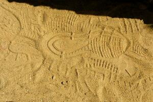 se av en sko fotavtryck i de sand. textur av gul sand med spår av annorlunda skor. foto