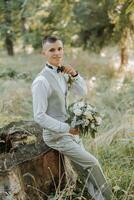 eleganta brudgum är framställning för de bröllop ceremoni. en lyxig man i en väst innehav en slips med en bukett av blommor i hans händer. plats för text. bröllop dag. foto