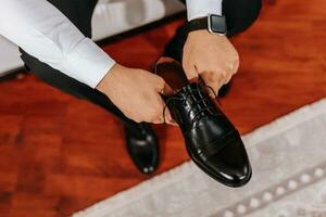 manlig händer innehav svart skor. elektronisk Kolla på på hand, fri Plats foto