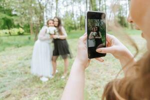 flickor på en bröllop ta foton på en smartphone. bröllop promenad i de skog